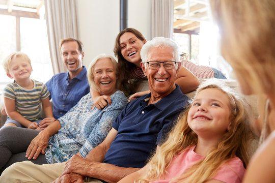 Three generations of a family laughing together on a sofa