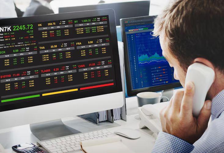 A trader watching stock prices on several screens